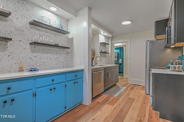 kitchen featuring blue cabinetry, appliances with stainless steel finishes, light hardwood / wood-style flooring, and sink