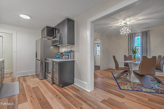 kitchen with a chandelier, stainless steel appliances, and light hardwood / wood-style floors