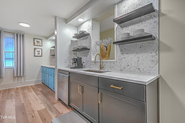 kitchen featuring tasteful backsplash, dishwasher, sink, and light wood-type flooring