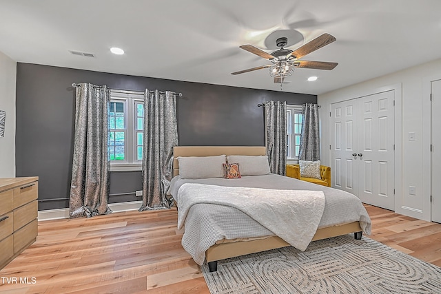 bedroom with a closet, light hardwood / wood-style floors, multiple windows, and ceiling fan