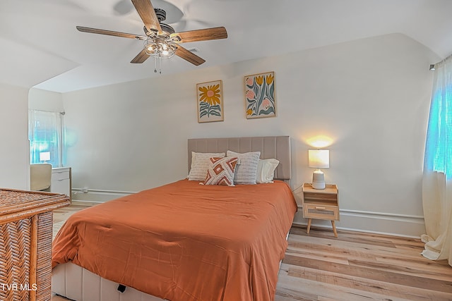 bedroom featuring light hardwood / wood-style flooring, multiple windows, lofted ceiling, and ceiling fan