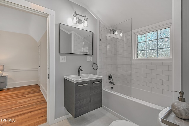 bathroom with hardwood / wood-style floors, vanity, tiled shower / bath, and vaulted ceiling