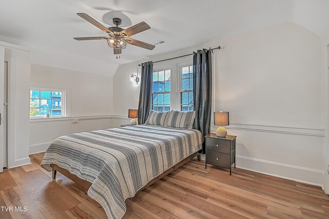 bedroom with light hardwood / wood-style flooring, multiple windows, lofted ceiling, and ceiling fan