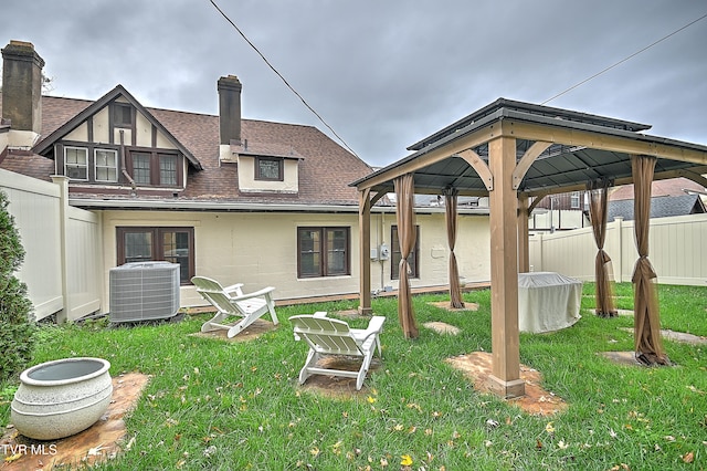 back of property featuring a gazebo, cooling unit, and a lawn