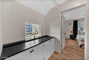 kitchen featuring white cabinets, light hardwood / wood-style floors, and vaulted ceiling