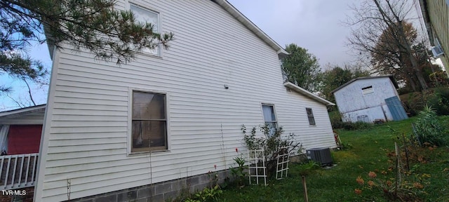 view of side of home featuring central AC unit and a yard