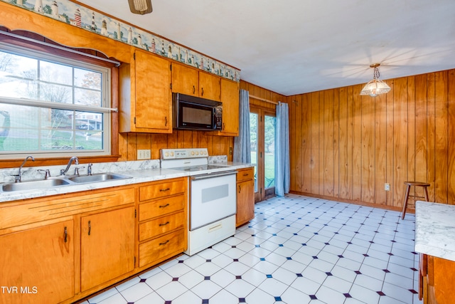 kitchen featuring wood walls, sink, decorative light fixtures, and white range with electric cooktop