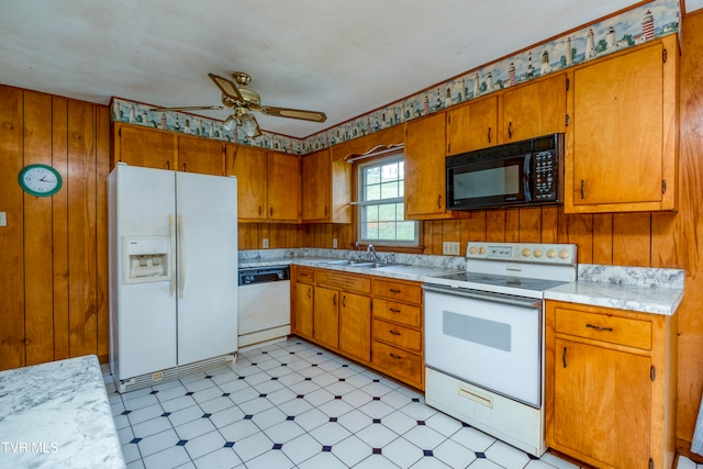 kitchen with sink, white appliances, wooden walls, and ceiling fan