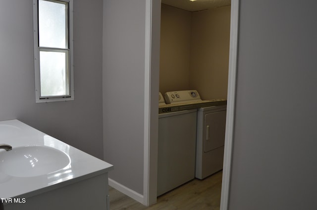 washroom with sink, light hardwood / wood-style flooring, and independent washer and dryer