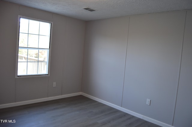 empty room featuring a textured ceiling and hardwood / wood-style flooring