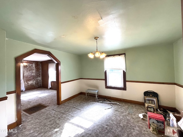 unfurnished room with carpet flooring and a chandelier