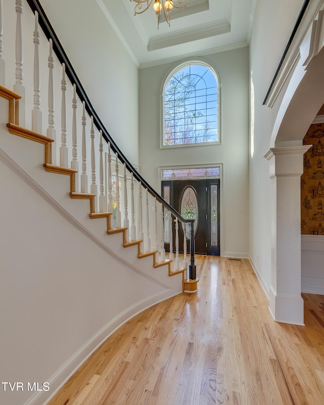 entryway with light hardwood / wood-style floors, ornamental molding, and a tray ceiling