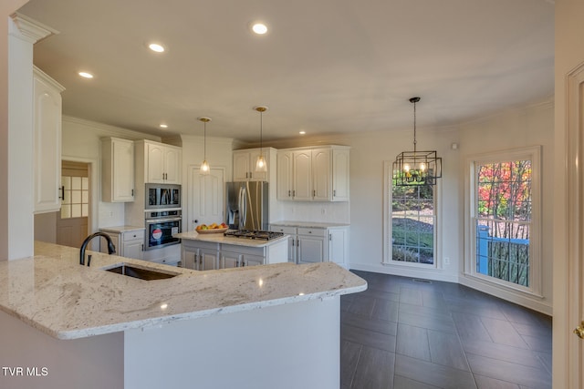 kitchen with stainless steel appliances, light stone counters, hanging light fixtures, sink, and a kitchen island