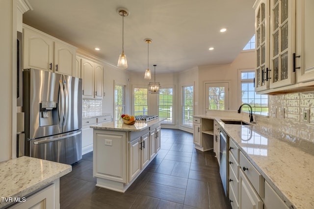 kitchen featuring stainless steel appliances, light stone counters, sink, and tasteful backsplash