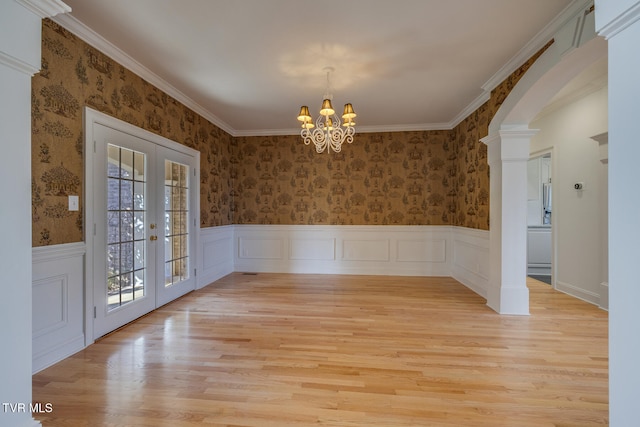 unfurnished dining area with french doors, light hardwood / wood-style flooring, crown molding, and an inviting chandelier