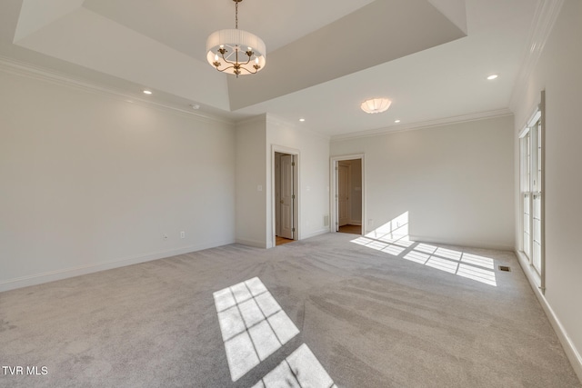 empty room featuring light colored carpet, a notable chandelier, crown molding, and a tray ceiling