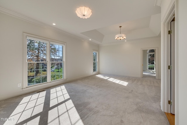 carpeted spare room with a notable chandelier, crown molding, and a tray ceiling