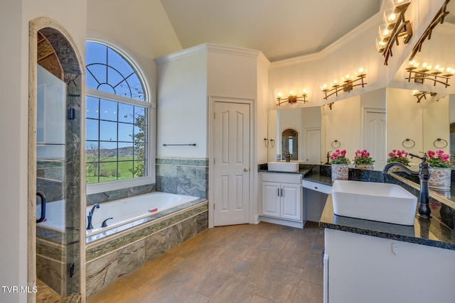 bathroom featuring ornamental molding, vanity, lofted ceiling, and a relaxing tiled tub