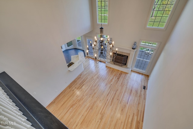 living room with light wood-type flooring, a wealth of natural light, a high ceiling, and an inviting chandelier