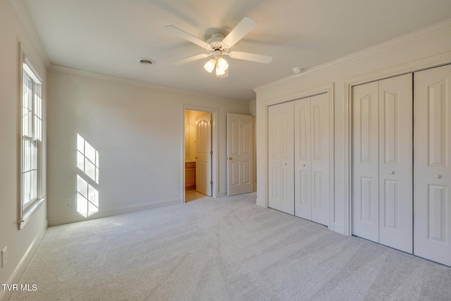 unfurnished bedroom featuring ornamental molding, multiple windows, light colored carpet, and ceiling fan