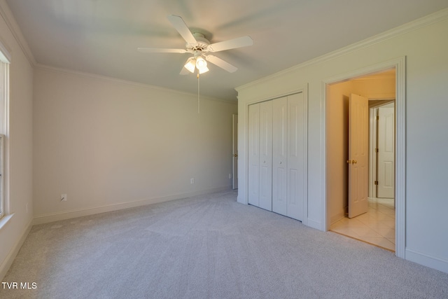 unfurnished bedroom with light carpet, ceiling fan, crown molding, and a closet