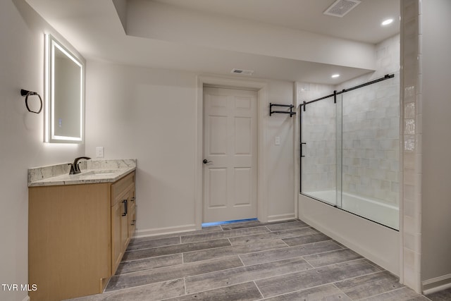 bathroom featuring wood-type flooring, combined bath / shower with glass door, and vanity