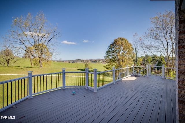 wooden terrace featuring a lawn and a rural view