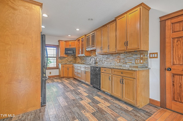 kitchen featuring black appliances, dark hardwood / wood-style flooring, light stone countertops, and backsplash