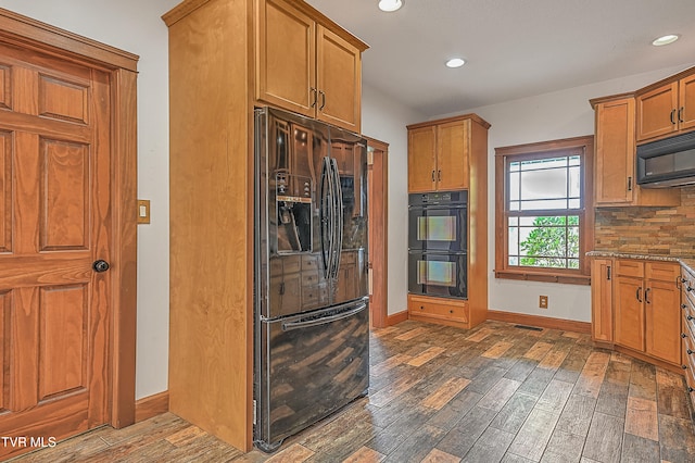 kitchen featuring decorative backsplash, dark wood-type flooring, black appliances, and stone countertops