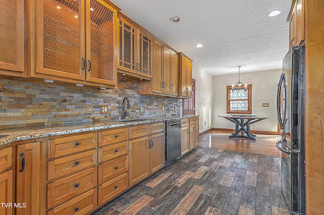 kitchen featuring sink, dishwasher, dark wood-type flooring, black fridge, and decorative light fixtures