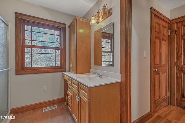 bathroom featuring tile patterned flooring, vanity, an enclosed shower, and a textured ceiling