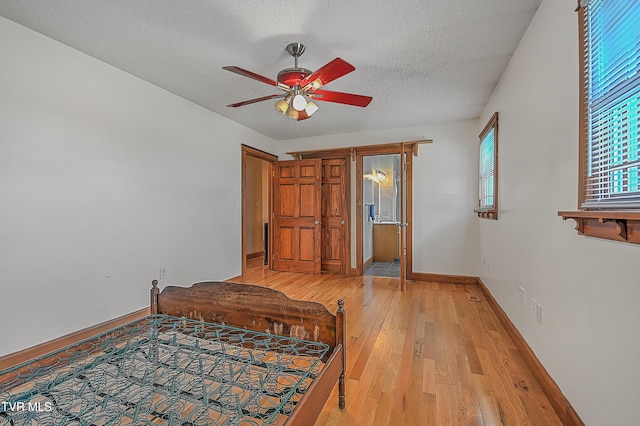 bedroom with a textured ceiling, light hardwood / wood-style floors, and ceiling fan