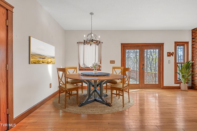 dining space with a chandelier, french doors, a textured ceiling, and light hardwood / wood-style flooring