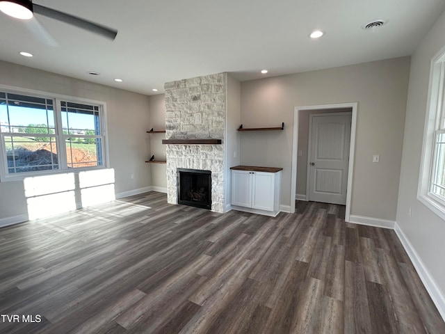 unfurnished living room featuring a fireplace, dark hardwood / wood-style floors, and ceiling fan