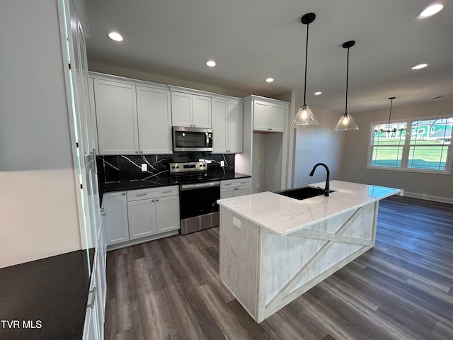 kitchen featuring a kitchen island with sink, white cabinets, sink, appliances with stainless steel finishes, and dark hardwood / wood-style flooring