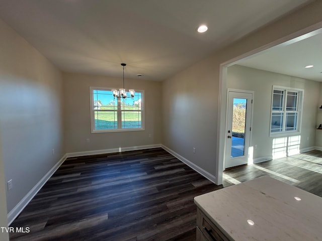 unfurnished dining area with a wealth of natural light, dark wood-type flooring, and a notable chandelier