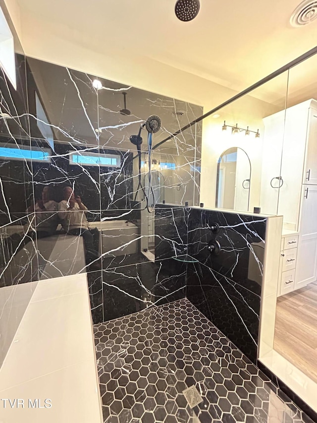 bathroom with hardwood / wood-style floors, vanity, and a tile shower