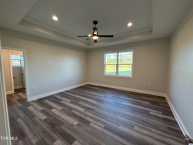 unfurnished room featuring ornamental molding, dark hardwood / wood-style floors, ceiling fan, and a tray ceiling