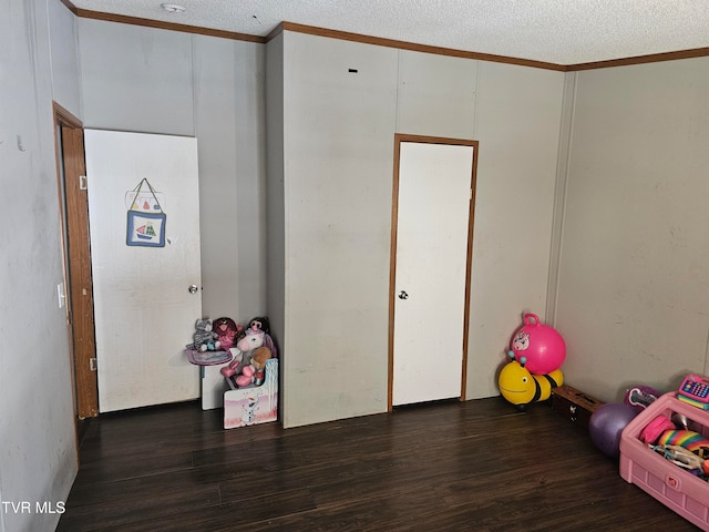 playroom featuring a textured ceiling, dark hardwood / wood-style flooring, and crown molding