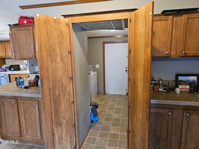 kitchen featuring a textured ceiling, tile countertops, and washing machine and clothes dryer