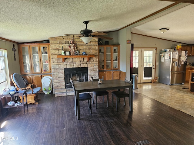 dining area featuring a textured ceiling, vaulted ceiling, ceiling fan, wood-type flooring, and a fireplace