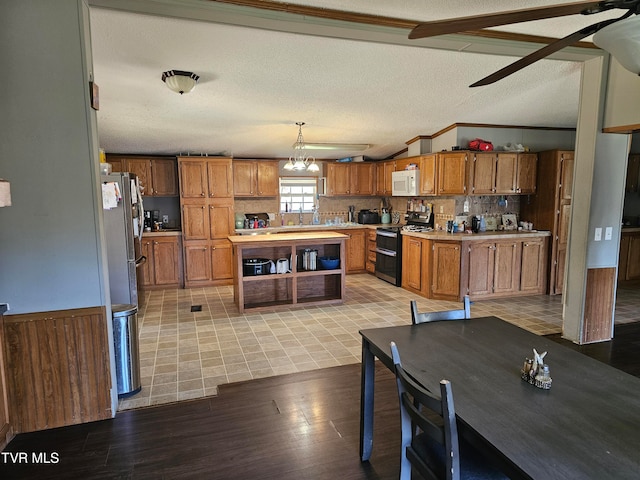 kitchen featuring ceiling fan with notable chandelier, light wood-type flooring, a textured ceiling, decorative light fixtures, and stainless steel appliances