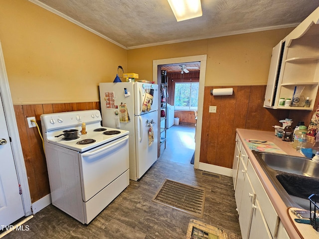 kitchen with wood walls, white cabinetry, white appliances, and a textured ceiling