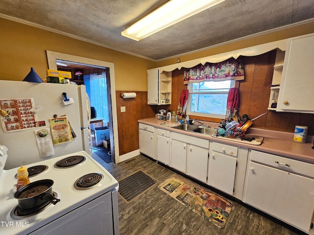 kitchen with white cabinets, a textured ceiling, wooden walls, sink, and white appliances