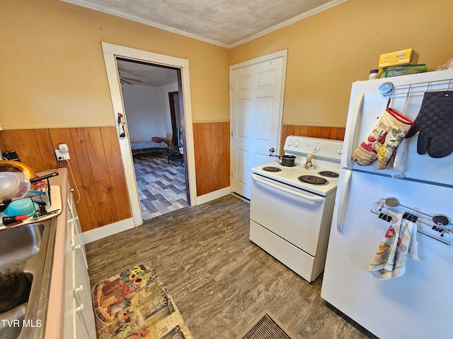 kitchen featuring dark hardwood / wood-style flooring, a textured ceiling, wooden walls, ornamental molding, and white appliances