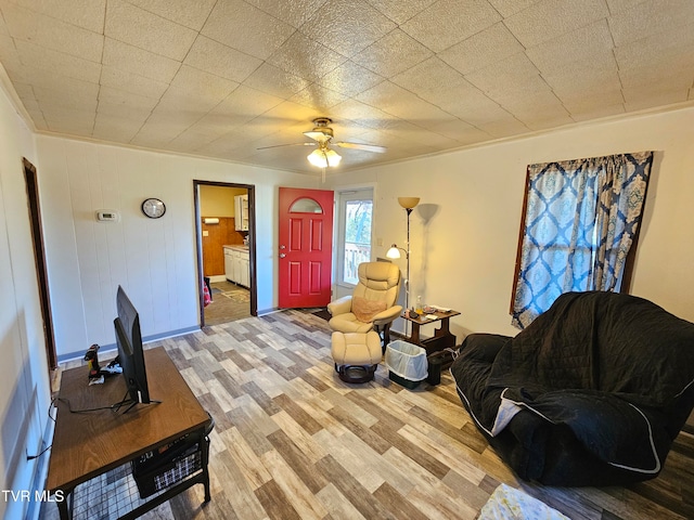 living room with ornamental molding, wood-type flooring, ceiling fan, and wooden walls