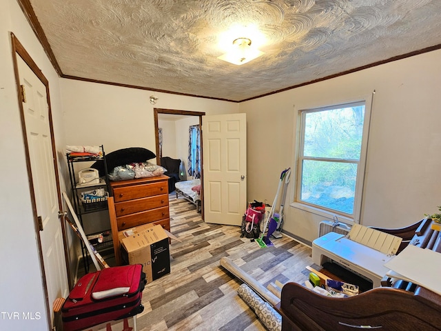 bedroom with a textured ceiling, light wood-type flooring, and crown molding