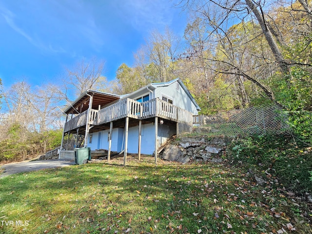 rear view of house featuring a lawn and a deck