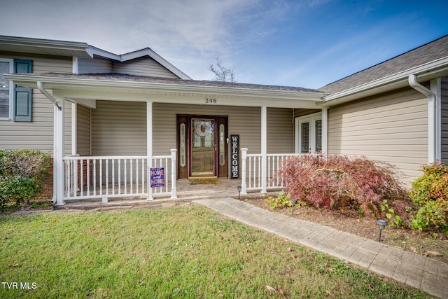 doorway to property with a lawn and a porch