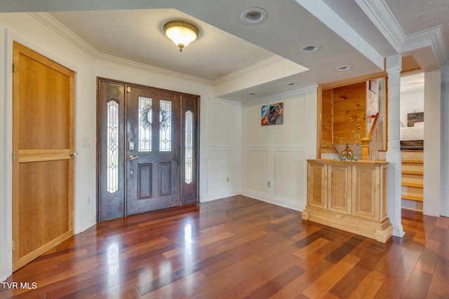 foyer with ornamental molding, ornate columns, and dark wood-type flooring